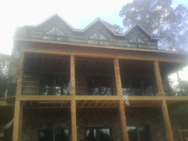 Dormers and porch framing on a large log home under construction — Roof Coating work by our crew in Minocqua