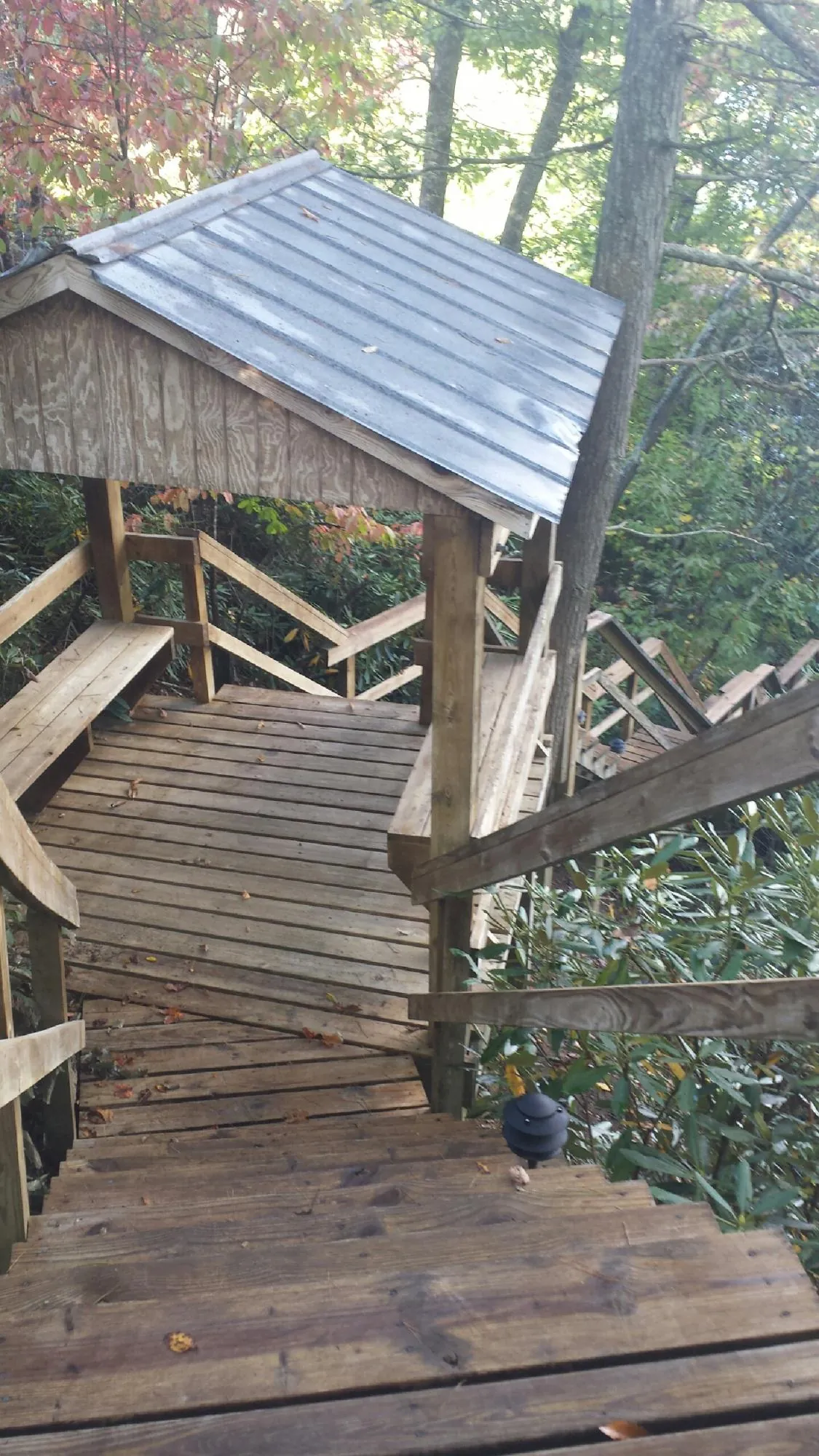 Metal roofed shelter over wooden steps on a wooded walkway — Skylight Repair & Installation work by our crew in Minocqua