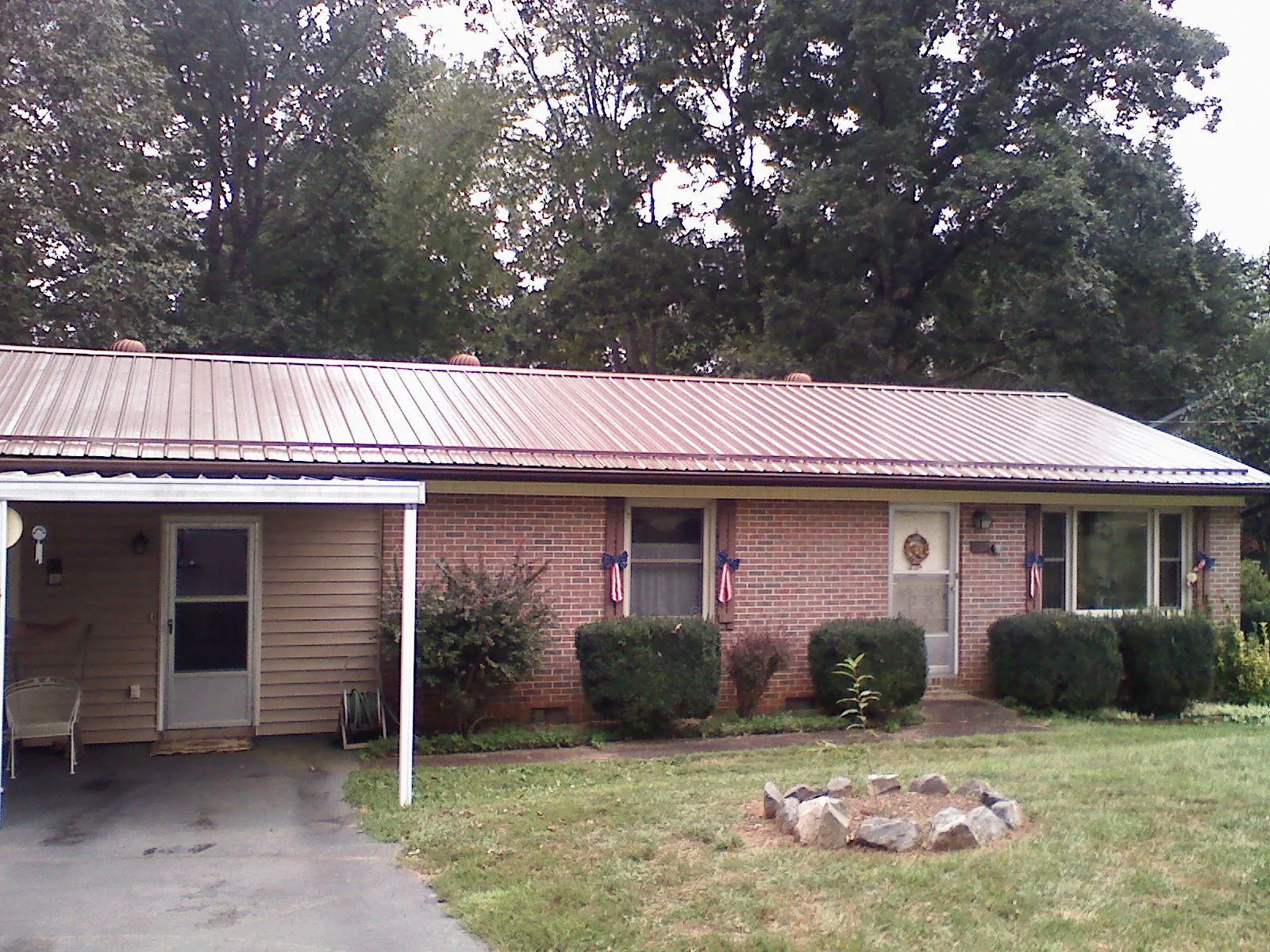 Bronze metal roof and carport on a brick ranch home — Roof Repair work by our crew in Minocqua