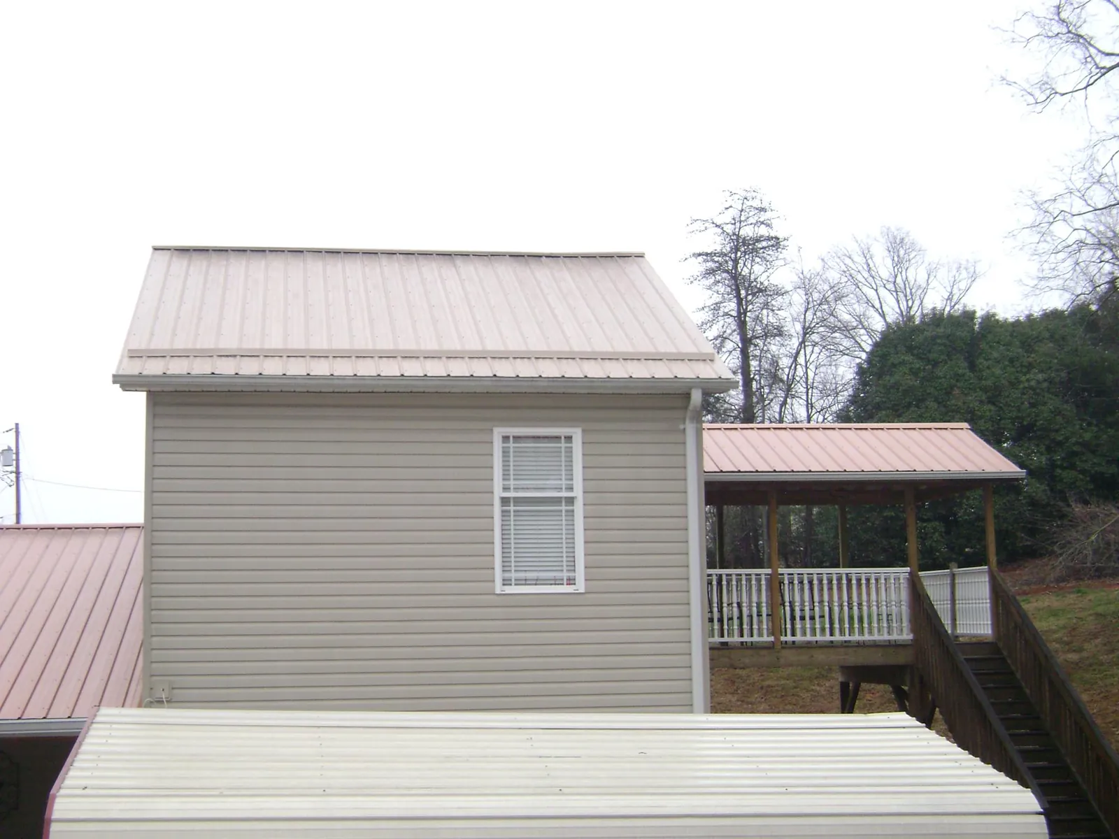 Tan metal roofs on a two story addition and attached porch, from a Roof Replacement job in Minocqua
