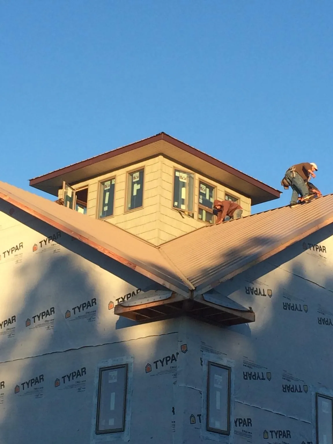 Roofers working around a rooftop cupola on a new metal roof at sunset — Roof Waterproofing in Minocqua by Roofing Brothers